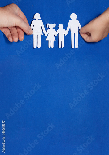 A child and a mother hold hands with a family cut out of paper. Family home, adoption, foster family, autism support, happy family