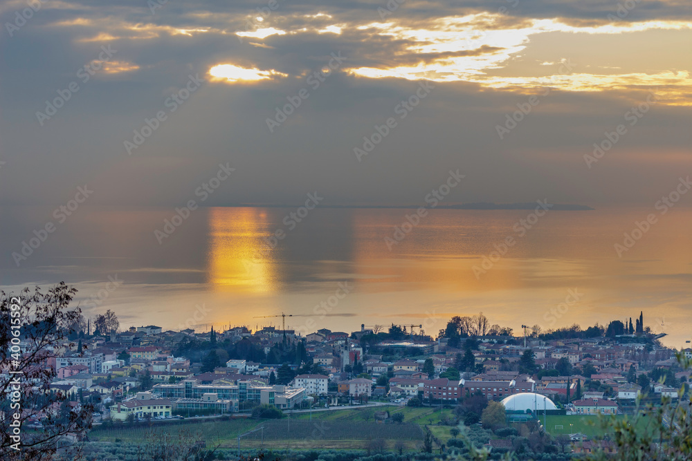 View of Bardolino from the hills. On these hills there are the vineyards of the famous Bardolino wine. The sunset is reflected in Lake Garda.