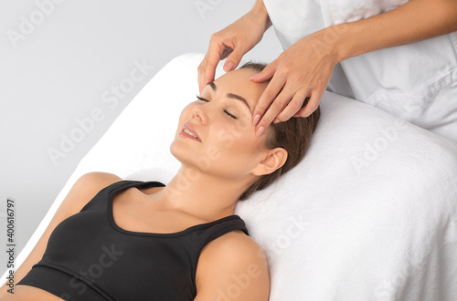 Masseur makes a relaxing massage on the face, neck, shoulders and collarbones of a young beautiful woman in a spa. Cosmetology and massage concept. photo