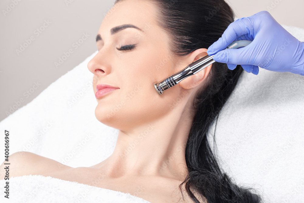 The cosmetologist makes the procedure Microdermabrasion of the face skin of a beautiful girl in a beauty salon.Cosmetology and professional skin care. The cosmetologist makes the procedure Microdermabrasion of the face skin of a beautiful girl in a beauty salon.Cosmetology and professional skin care.