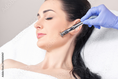 The cosmetologist makes the procedure Microdermabrasion of the face skin of a beautiful girl in a beauty salon.Cosmetology and professional skin care.