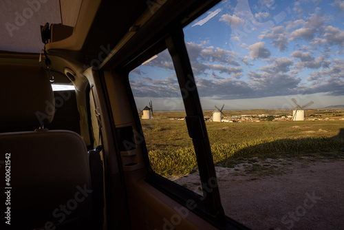 Exterior view of famous windmills on landscape in the town of Campo de Criptana at sunrise from a camper van window, Ciudad Real, Spain