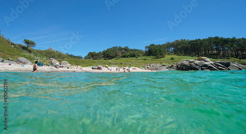 Fototapeta Naklejka Na Ścianę i Meble -  Spain Galicia coastline, beach with tourists in summer vacations seen from water surface, Atlantic ocean, Bueu, Pontevedra province, Praia do Ancoradoiro