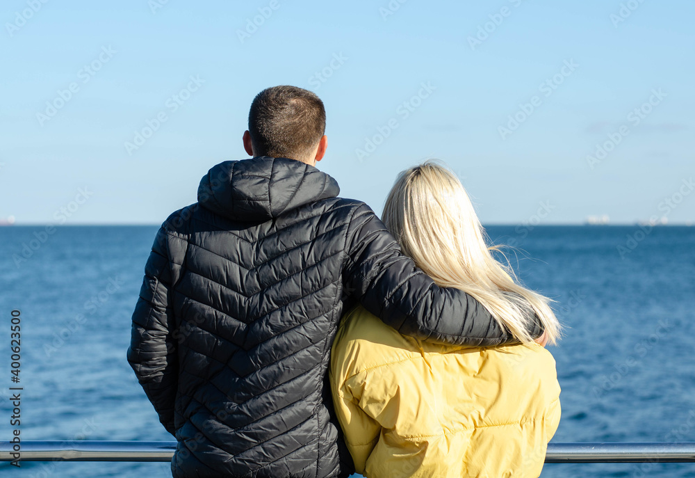A guy and a girl are walking by the sea. A loving couple looks at the sea.