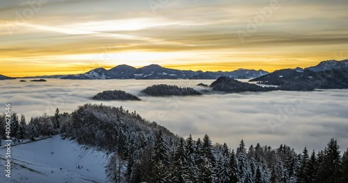 Wallpaper Mural Time lapse of inversion clouds moving in valley, Slovenia. Beautiful Alps mountains covered with snow in the distance. Kids sledding on slope at sunset. Static, wide angle Torontodigital.ca