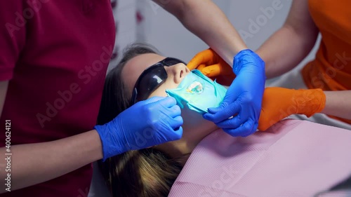Close up Dentist orthodontist hands putting rubber dam retractor in girl mouth. Closeup view preparation before examination and treatment in a dental clinic of a female patient. photo