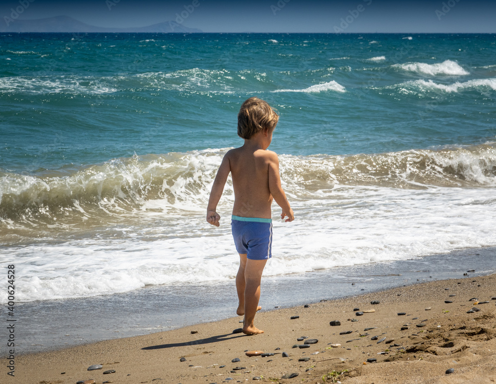 Young boy walking at shoreline