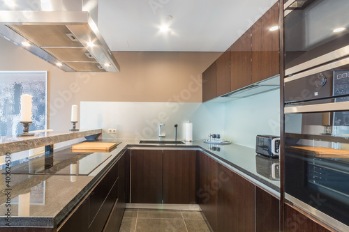 Modern kitchen with a marble counter, equipped with cooker, oven, fridge