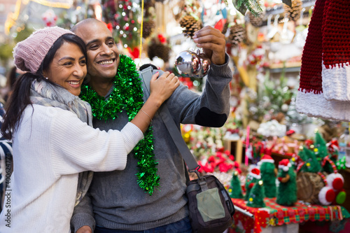 Emotional happy couple buying christmas balls at christmas street fair