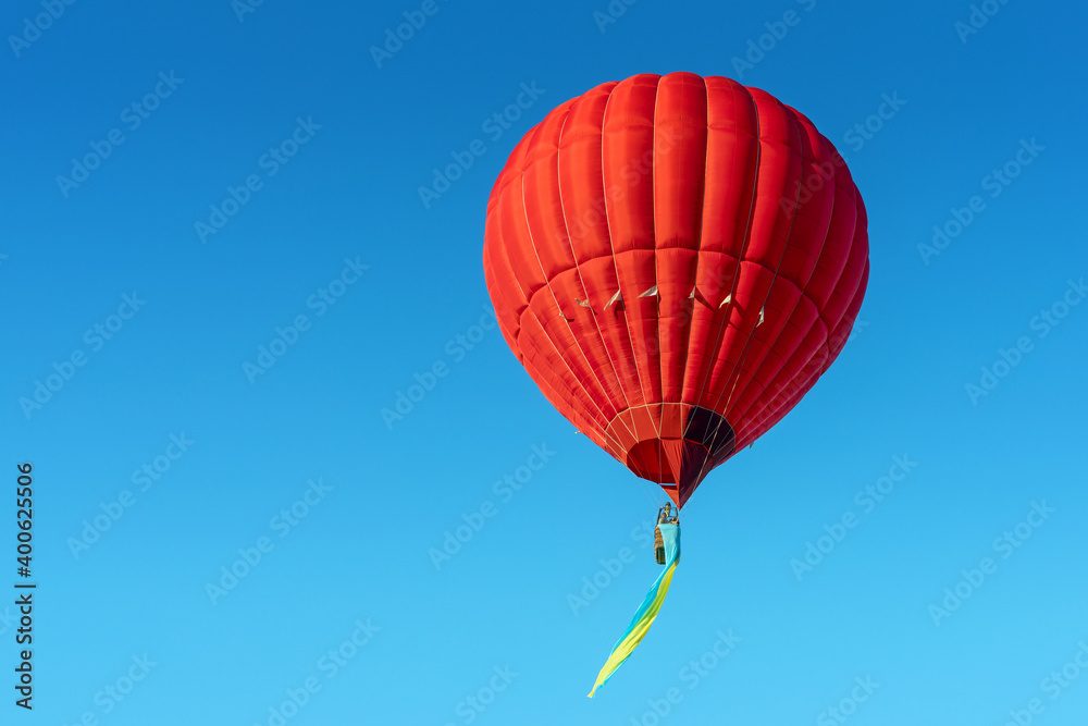 Fototapeta premium Red hot air balloon with the flag of Ukraine on a blue sky background