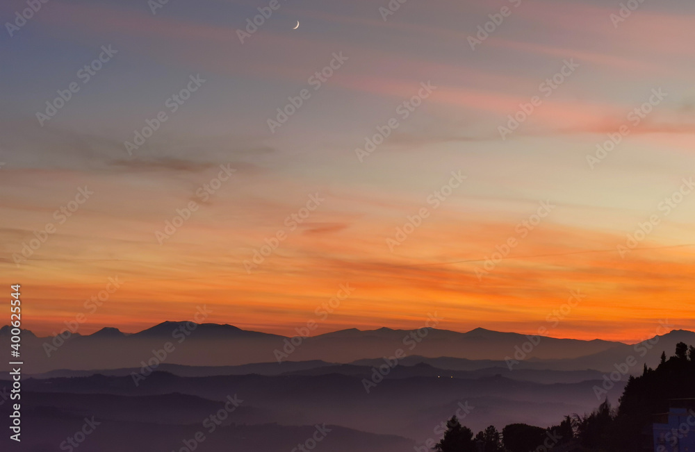 Obraz premium Tramonto sulle montagne, colline e valli dell'Appennino con la luna nel cielo