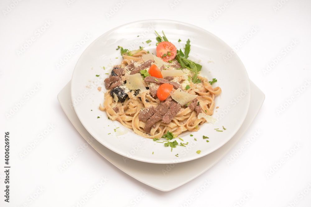 Pasta with beef, prunes and parmesan cheese on a white plate. Located on a white background. Can be used in the restaurant menu. Pasta with beef, prunes and parmesan cheese on a white plate. Located on a white background. Can be used in the restaurant menu.
