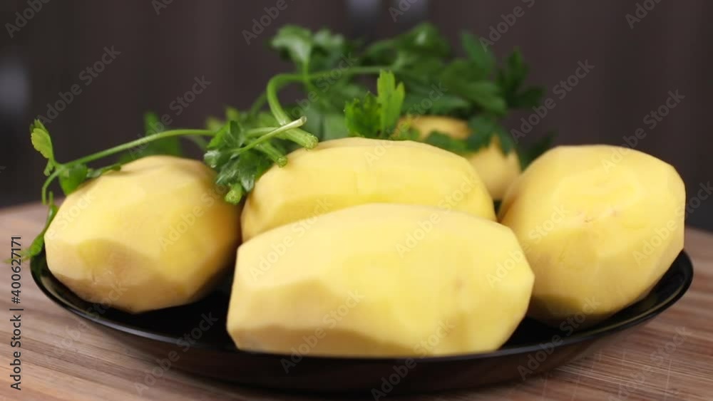 peeled yukon gold potatoes and green parsley rotating close-up on wooden background peeled yukon gold potatoes and green parsley rotating close-up on wooden background