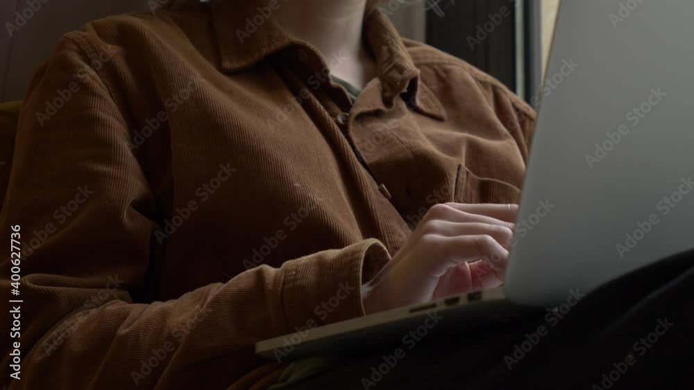 Woman working with laptop near a window at home Woman working with laptop near a window at home