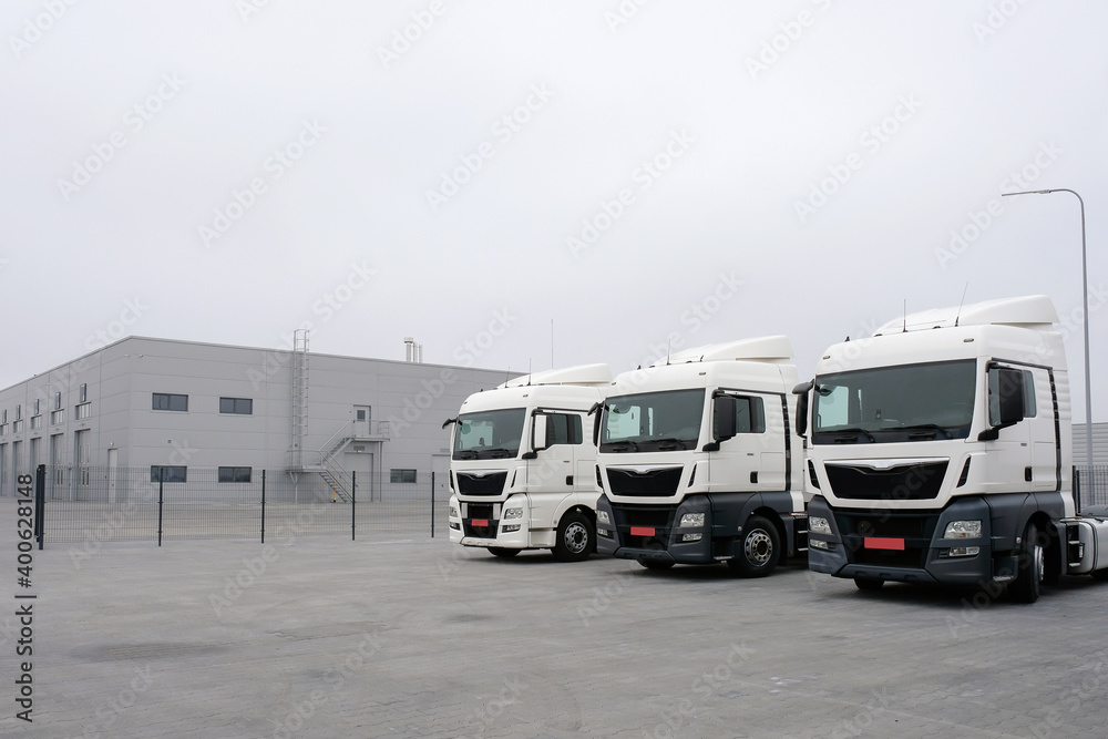 Trucks stand in a row at a truck stop. Cargo semi-trailers for delivery and loading of cargo, logistics, cargo transportation. Car service and truck maintenance