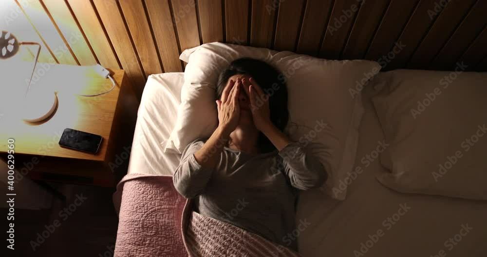 Worried sleepless woman in 30s lying in bed unable to sleep