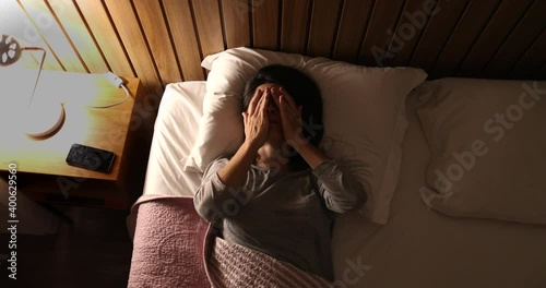 Worried sleepless woman in 30s lying in bed unable to sleep photo