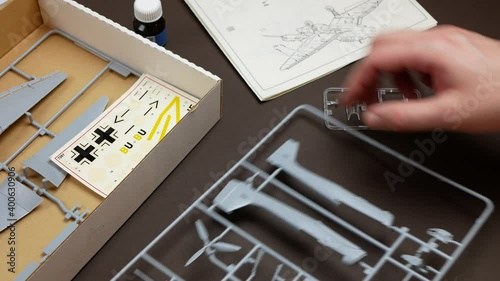 Preparation to build a plastic model airplane, Person examine a set of plastic sprues holding components to assemble and an instruction manual photo