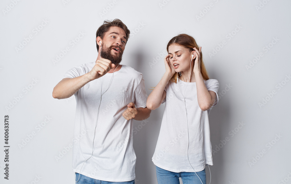 Fototapeta premium Happy friends in headphones listens to music and dances on a light background