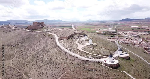 Aerial view of white cylindrical towers and pointed roofs of old Spanish windmills on background with Consuegra cityscape