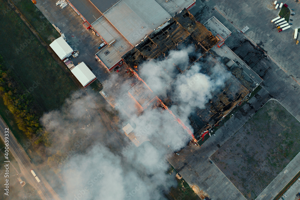 Aerial view of burning industrial building, fire with huge smoke from burned roof