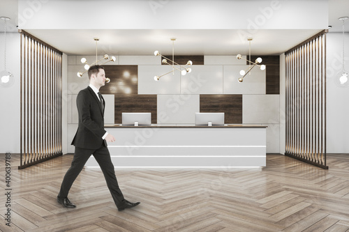 Businessman walking in luxury office hall with black reception desk