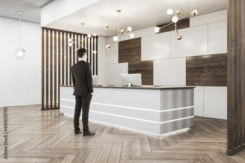 Businessman standing in office hall with reception desk