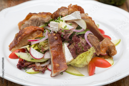 Mix leaves with pork roast slices, crackling, apple, Camembert cheese, cherry tomatoes, and apple vinaigrette