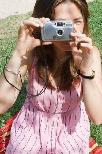 Young woman using an analog film camera  staring at camera