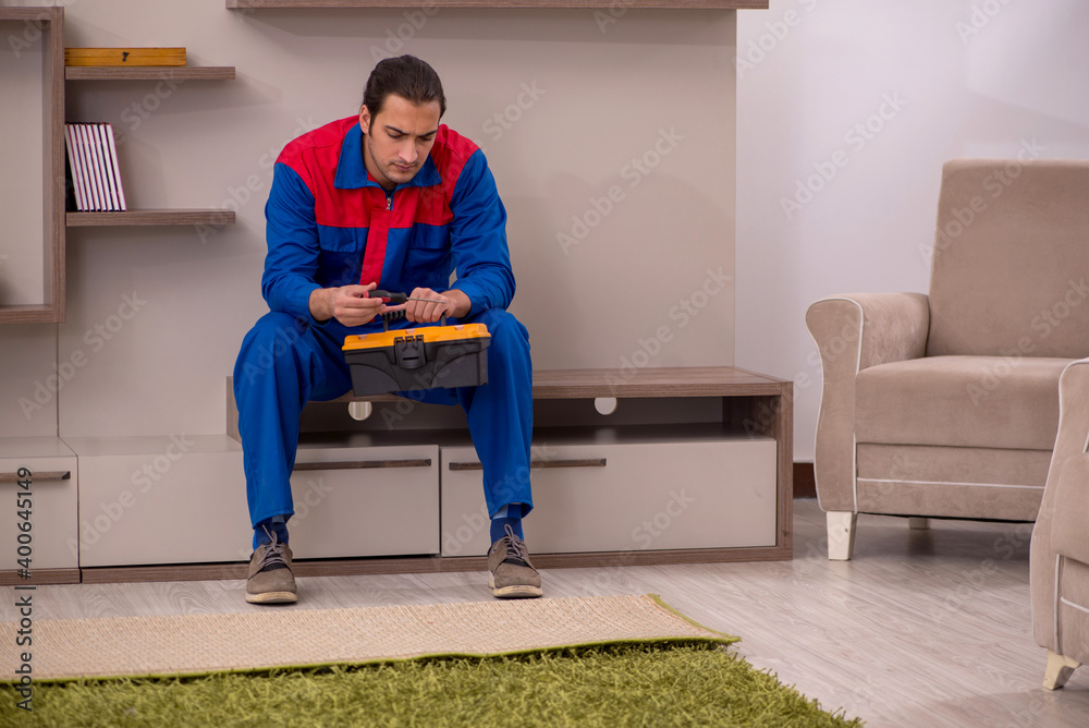 Young male contractor repairing furniture indoors