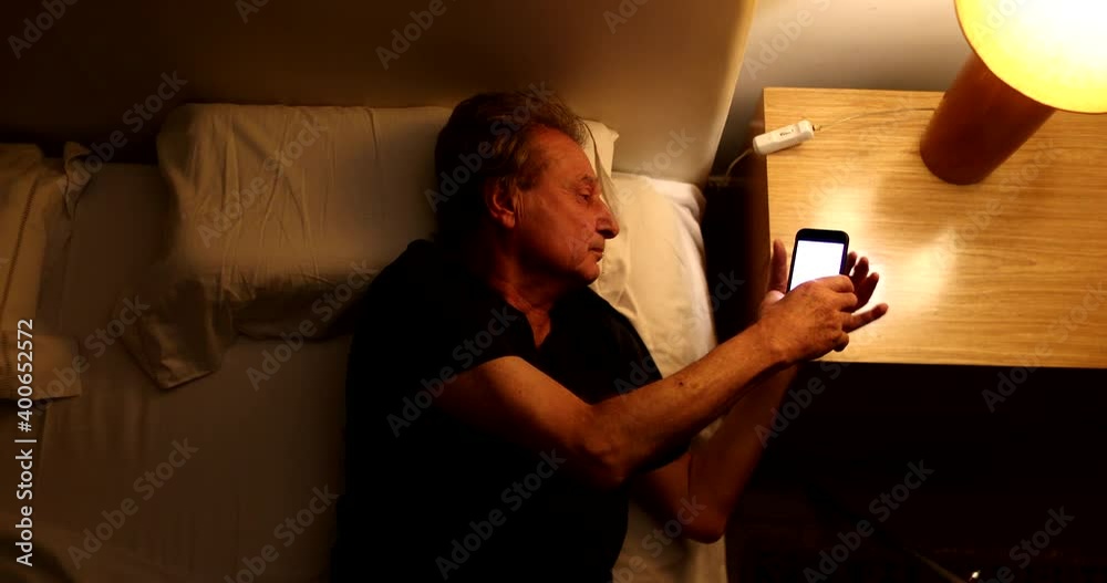 Man turning off phone and nightstand lamp light, person going to sleep Man turning off phone and nightstand lamp light, person going to sleep