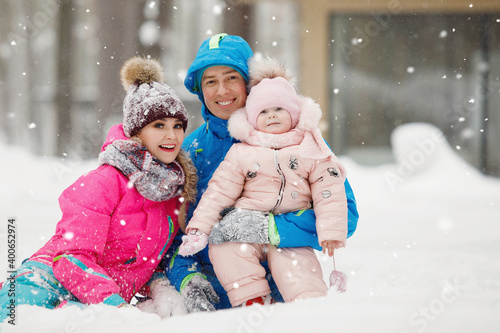 Family in winter clothes having fun, rejoice in the snowdrifts
