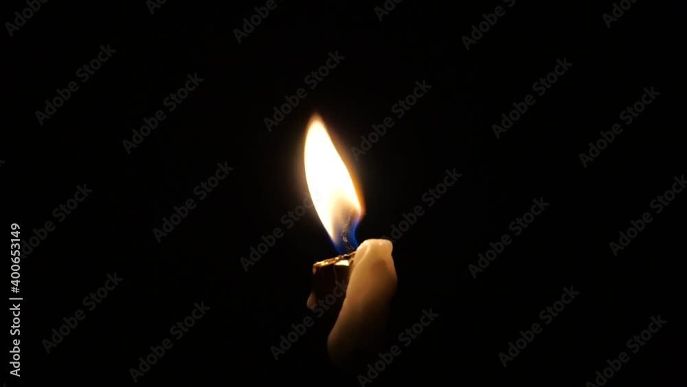 A person lighting up a single wax candle in the dark A person lighting up a single wax candle in the dark