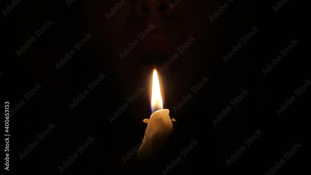 A man blowing out a single wax candle flame in the dark A man blowing out a single wax candle flame in the dark