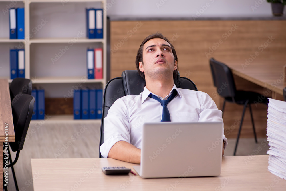 Obraz premium Young male employee unhappy with excessive work in the office