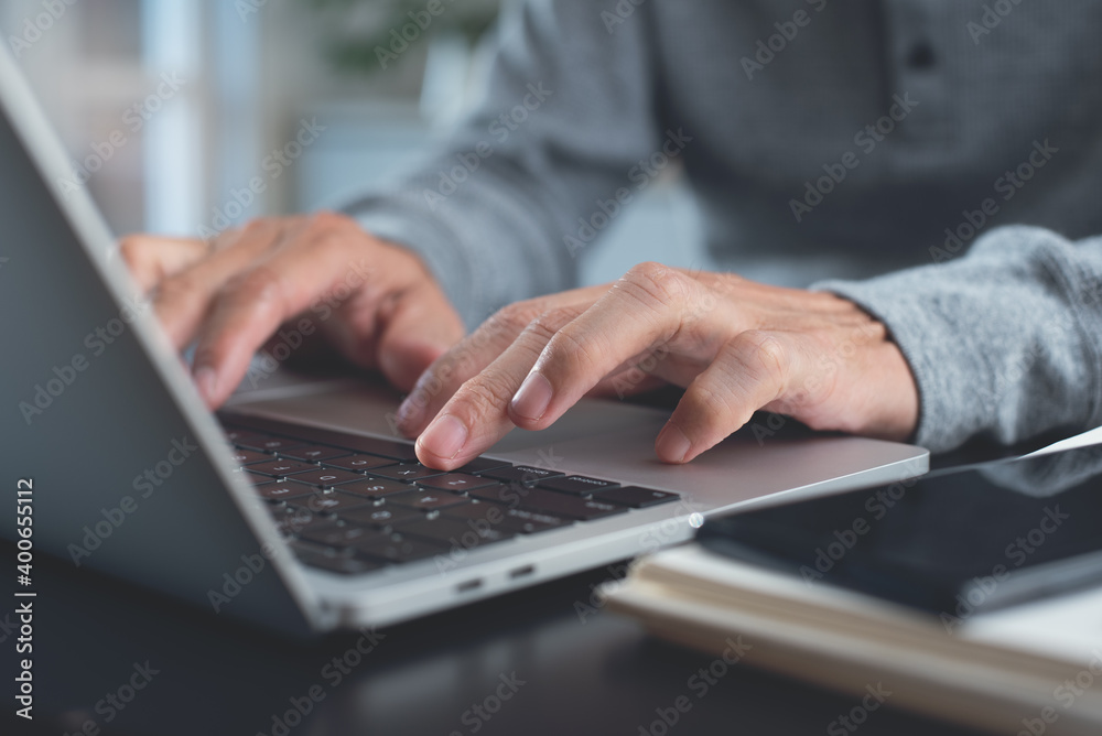Man hands typing on laptop computer keyboard, surfing the internet online working from home office