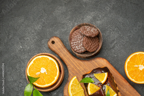 Overhead view of tasty cakes cut lemons with biscuits on cutting board on dark background
