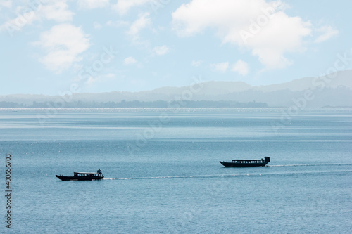 Passenger boats moving through vast river and hills in the background
