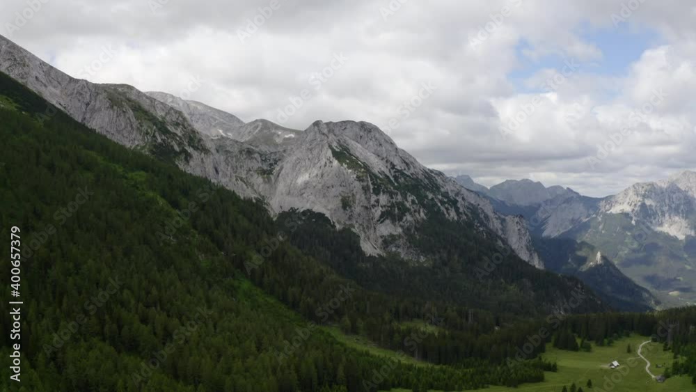 Aerial - Showing a really big mountain area in the Austrian alps. On the bottom you can see a big, flat area with a little hut Aerial - Showing a really big mountain area in the Austrian alps. On the bottom you can see a big, flat area with a little hut