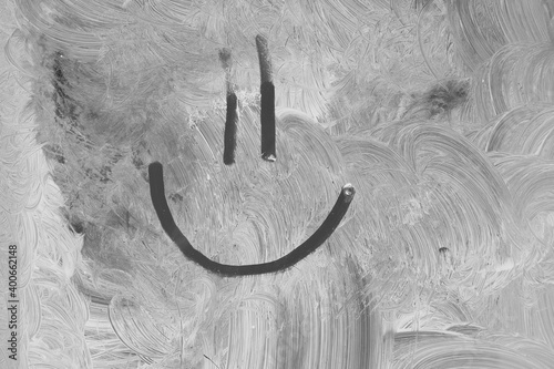 Closeup of a smiley face drawn on a whitewashed window.