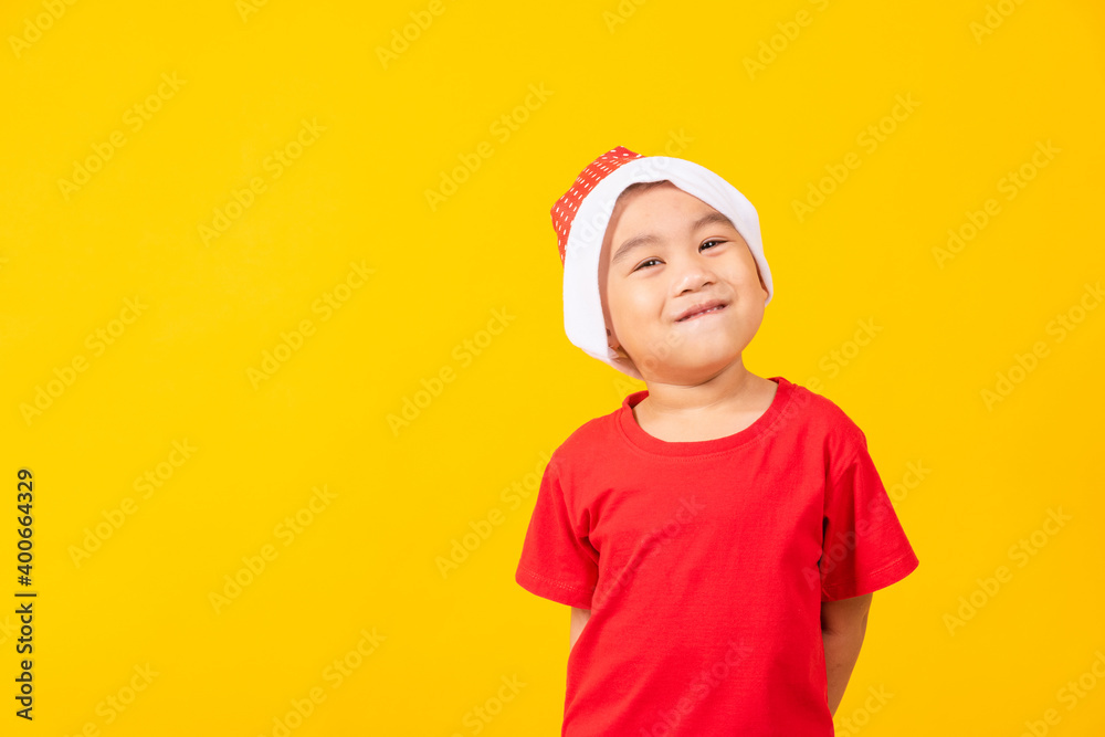 Kid dressed in red Santa Claus hat, Portrait of Asian little cute boy smile and excited the concept of holiday Christmas Xmas day or Happy new year, studio shot isolated on yellow background Kid dressed in red Santa Claus hat, Portrait of Asian little cute boy smile and excited the concept of holiday Christmas Xmas day or Happy new year, studio shot isolated on yellow background