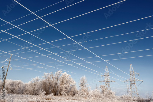High-voltage wires and poles are covered with frost on a frosty winter day.
