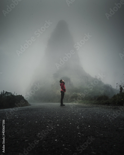 person walking in road with fog and silhouette of moutain