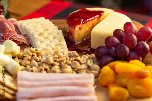 Board with Grape, Cookie, Jam, Bread, Peanut, Tangerine, Pieces of Oranges, Ham, Candle, Pine Cone, Cheese to eat at Christmas
