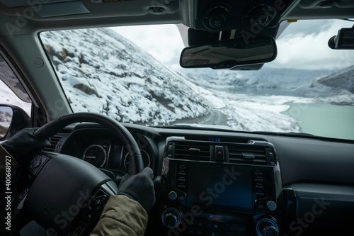 Fototapeta Naklejka Na Ścianę i Meble -  Driving off road car on snowing high altitude mountain trail on winter day