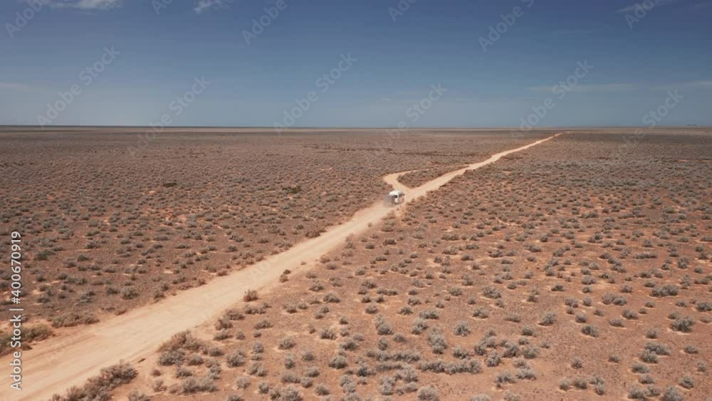 Aerial view following a RV, driving on a dusty desert road sunny day, in Australia - tracking, drone shot Aerial view following a RV, driving on a dusty desert road sunny day, in Australia - tracking, drone shot