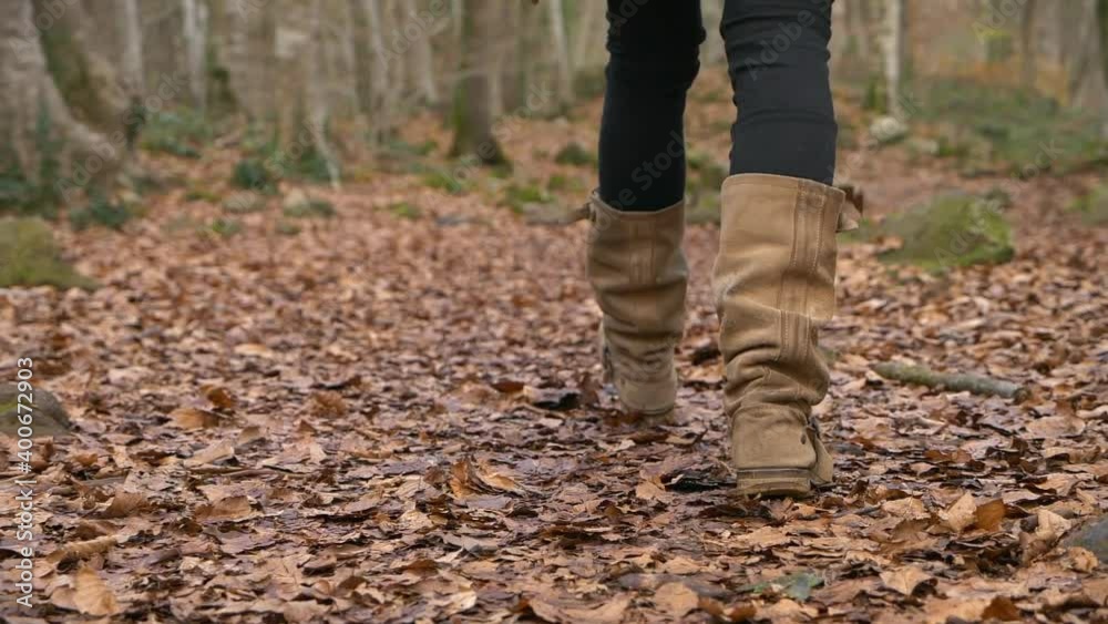 Woman in tall brown boots walks on autumn forest leaves, Slowmo with Copy Space Woman in tall brown boots walks on autumn forest leaves, Slowmo with Copy Space