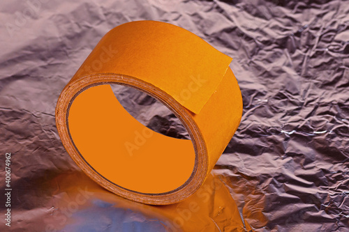 Roll of double-sided adhesive tape on a shiny surface close-up