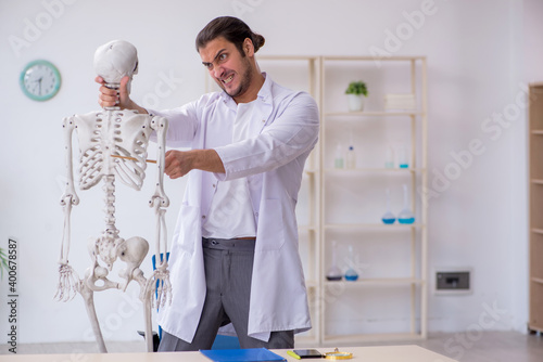 Young male doctor demonstrating human skeleton