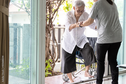 Asian caregiver help care to senior grandmother walk,woman holding hands of the old elderly for support,walking up from a different level floor,safety,prevent accident at nursing home,service concept. photo